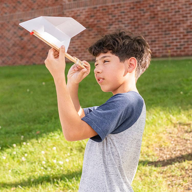 Mellow Monkey paper plane launcher made of FSC birch wood being held by a young boy outdoors