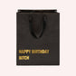 Mellow Monkey black heavy-duty kraft paper gift bag with gold foil Happy Birthday Bitch text and cotton handles.