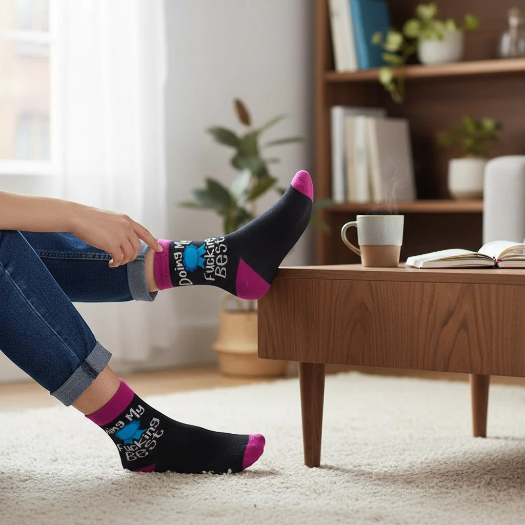 Mellow Monkey black crew socks with pink accents and Doing My Fucking Best text worn by a person in a cozy room