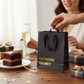 Mellow Monkey black heavy-duty gift bag with gold foil text Just Pretend You Like It and black cotton handles