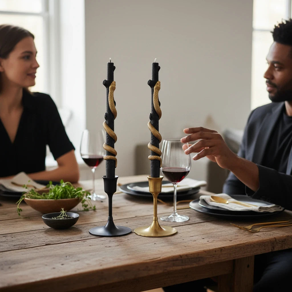 Mellow Monkey black twig-shaped taper candles with gold snake detail, set of two on a dining table with wine glasses.