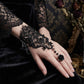 Mellow Monkey black lace fingerless ring-bracelet with a rose detail and bead accents on a model's hand.