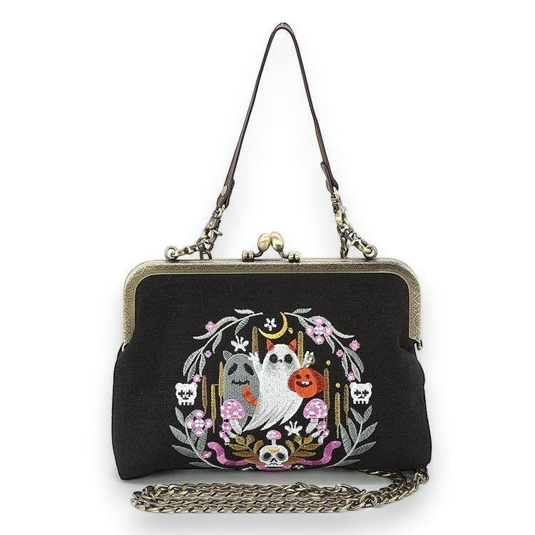 Mellow Monkey black linen kisslock bag featuring embroidered ghosts, snake, and floral wreath with bee detail.
