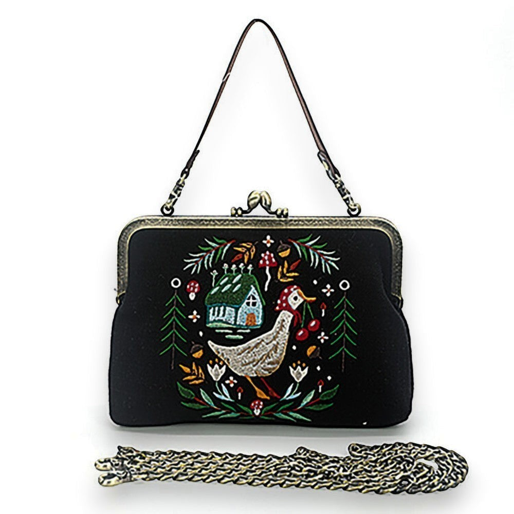 Mellow Monkey black linen kisslock bag featuring embroidered goose, cottage, and floral design with chain strap.