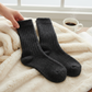 Mellow Monkey World's Softest black textured ragg crew socks resting on a soft cream faux fur blanket with coffee.