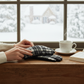 Mellow Monkey Blair plaid gloves with touchscreen fingertips resting on a wooden windowsill by a snowy window.