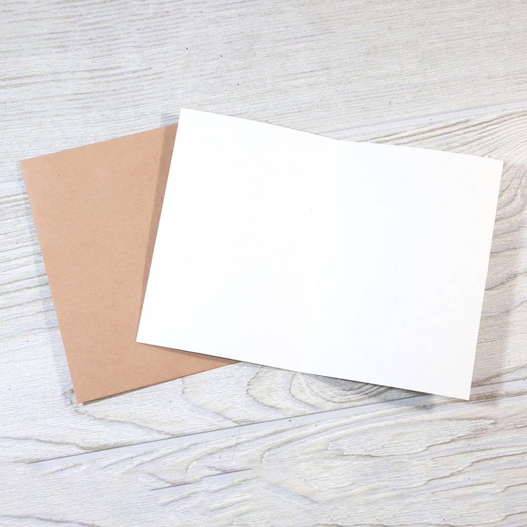 Mellow Monkey blank white greeting card with a kraft paper envelope on a rustic white wood background.