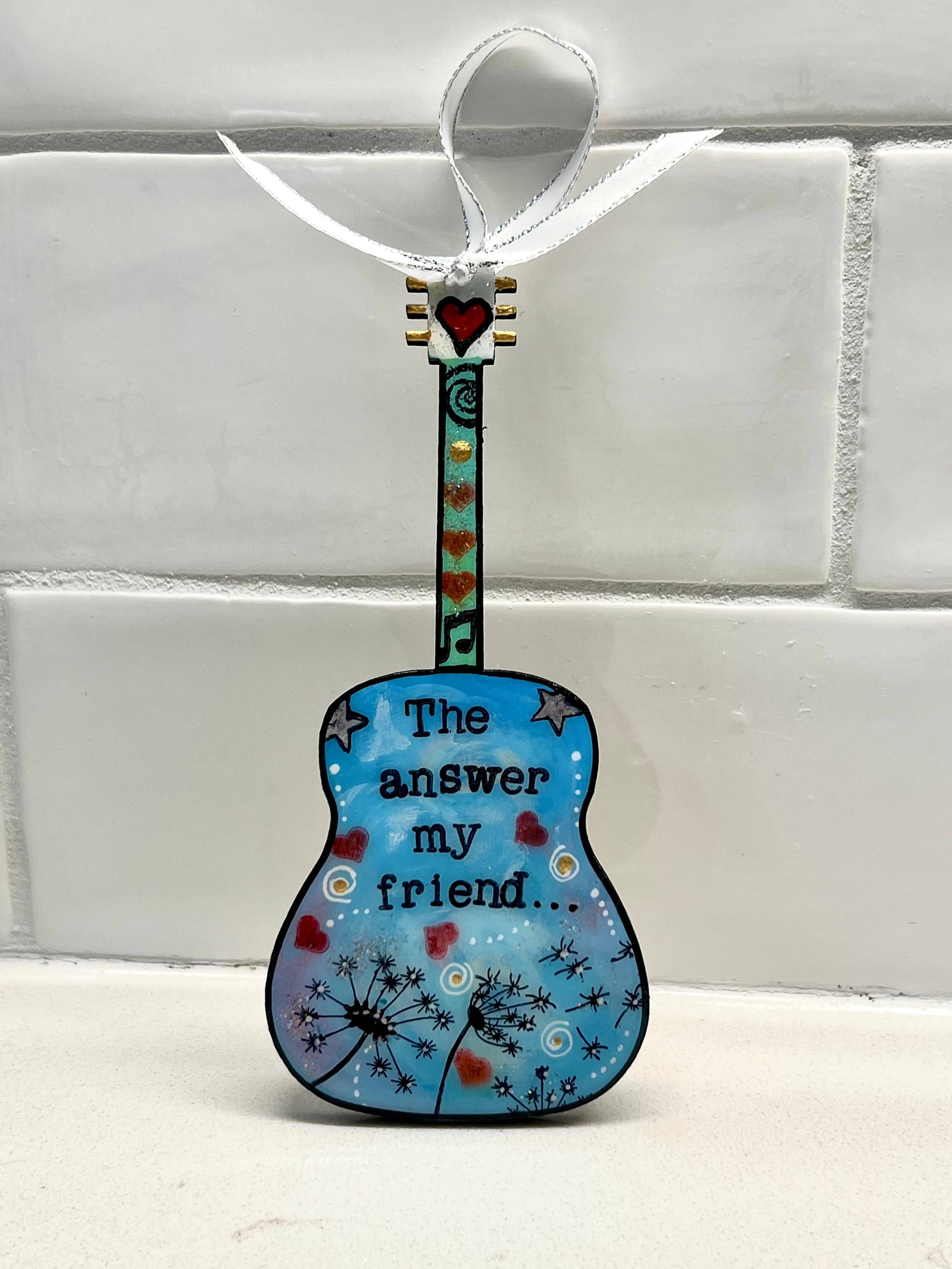 Mellow Monkey Blowing In The Wind guitar ornament with blue hand-painted finish, dandelion art, and heart accents.