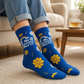 Mellow Monkey blue bamboo knit socks featuring a My Tummy Hurts message, rainbow, and yellow floral pattern.