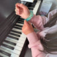 Mellow Monkey Blue Blast Feelzies sensory bracelet with glitter on a child's wrist while playing the piano.