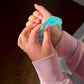 Mellow Monkey Blue Blast Feelzies sensory bracelet being squeezed on a wrist, featuring glittery blue slow-rebound material.