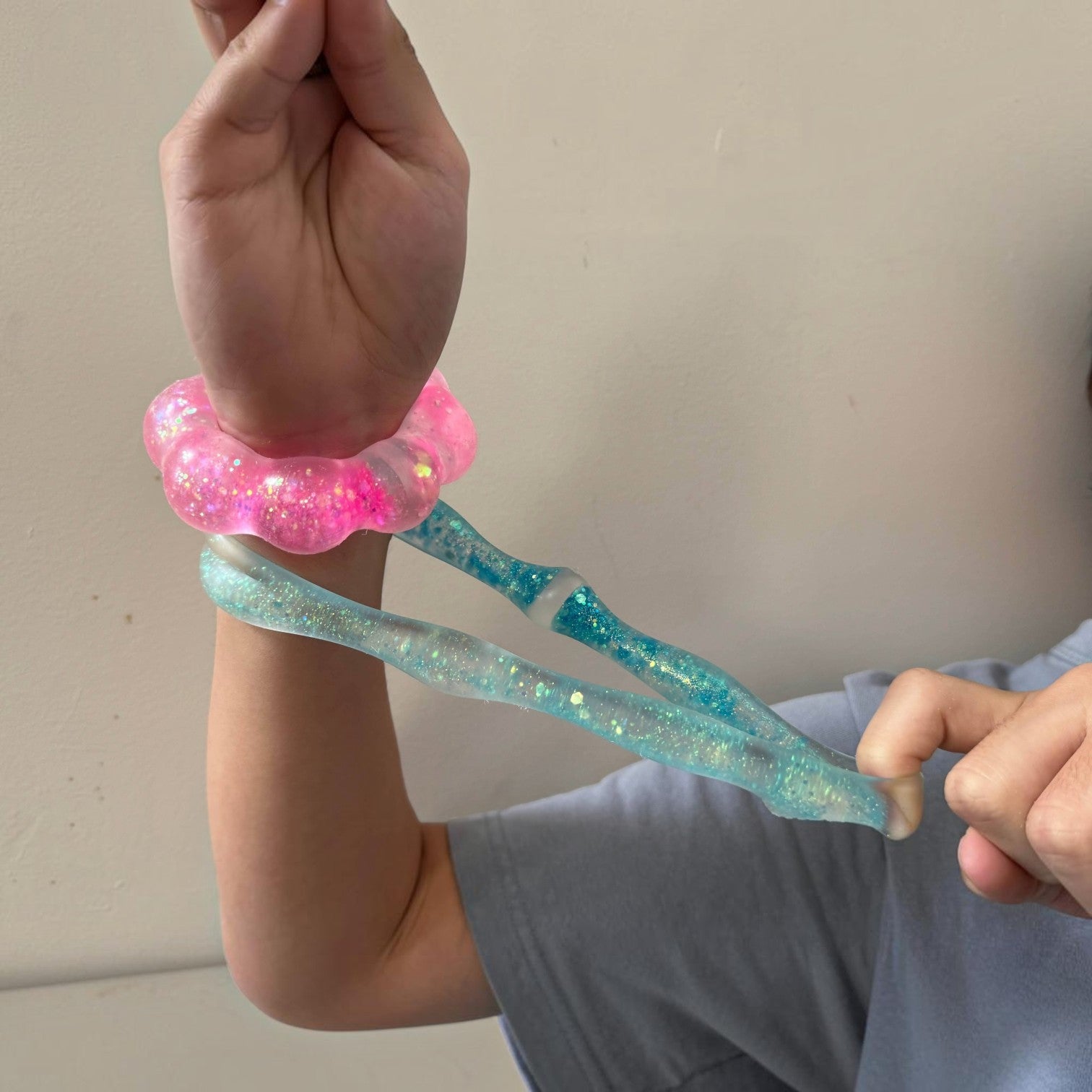 Mellow Monkey Blue Blast Feelzies sensory bracelet with glittery blue squishy material being stretched on a wrist
