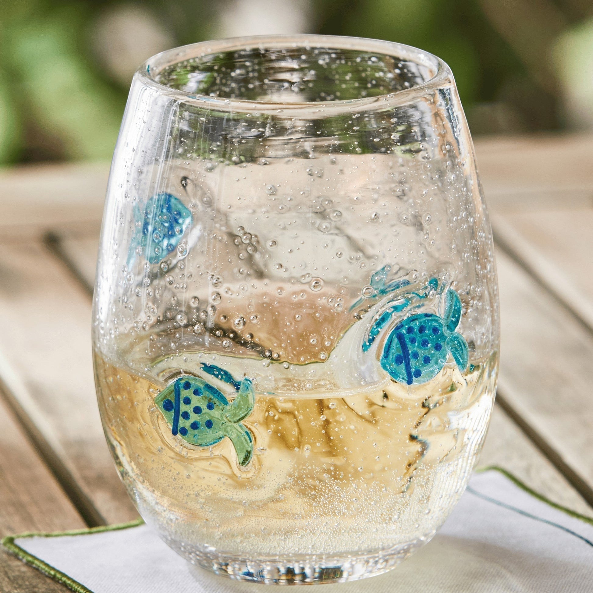 Mellow Monkey stemless wine glass featuring hand-blown clear glass with decorative blue fish and bubble accents.