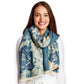 Mellow Monkey double-sided blue floral shawl scarf with eyelash fringe trim worn by a smiling woman