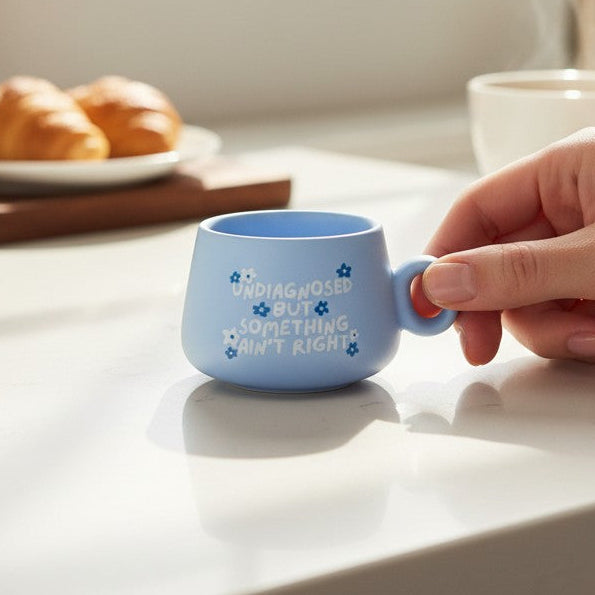 Mellow Monkey blue ceramic shot glass with floral design and humorous text on a kitchen counter