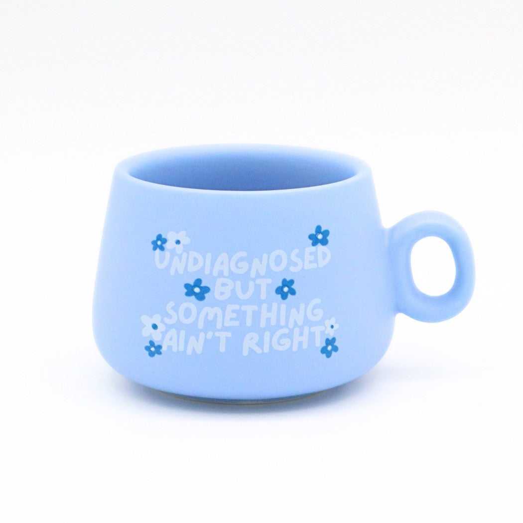 Mellow Monkey blue ceramic shot glass with white floral design and Undiagnosed But Something Ain't Right text