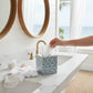 Mellow Monkey blue floral block print paper mache tissue box cover with gold painted edges on a bathroom vanity.