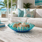Mellow Monkey handmade blue fused glass coral bowl filled with decorative shells on a white rustic coffee table.