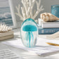Mellow Monkey blue glass jellyfish paperweight on a desk with ocean-themed decor