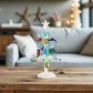 Mellow Monkey blue glass tree decoration featuring colorful sea life ornaments and LED lights on a wooden table.