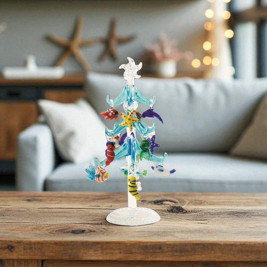 Mellow Monkey blue glass tree decoration featuring colorful sea life ornaments and LED lights on a wooden table.