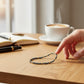 Mellow Monkey blue grey seed bead bracelet with 18K gold plated brass accents on a wooden desk with coffee