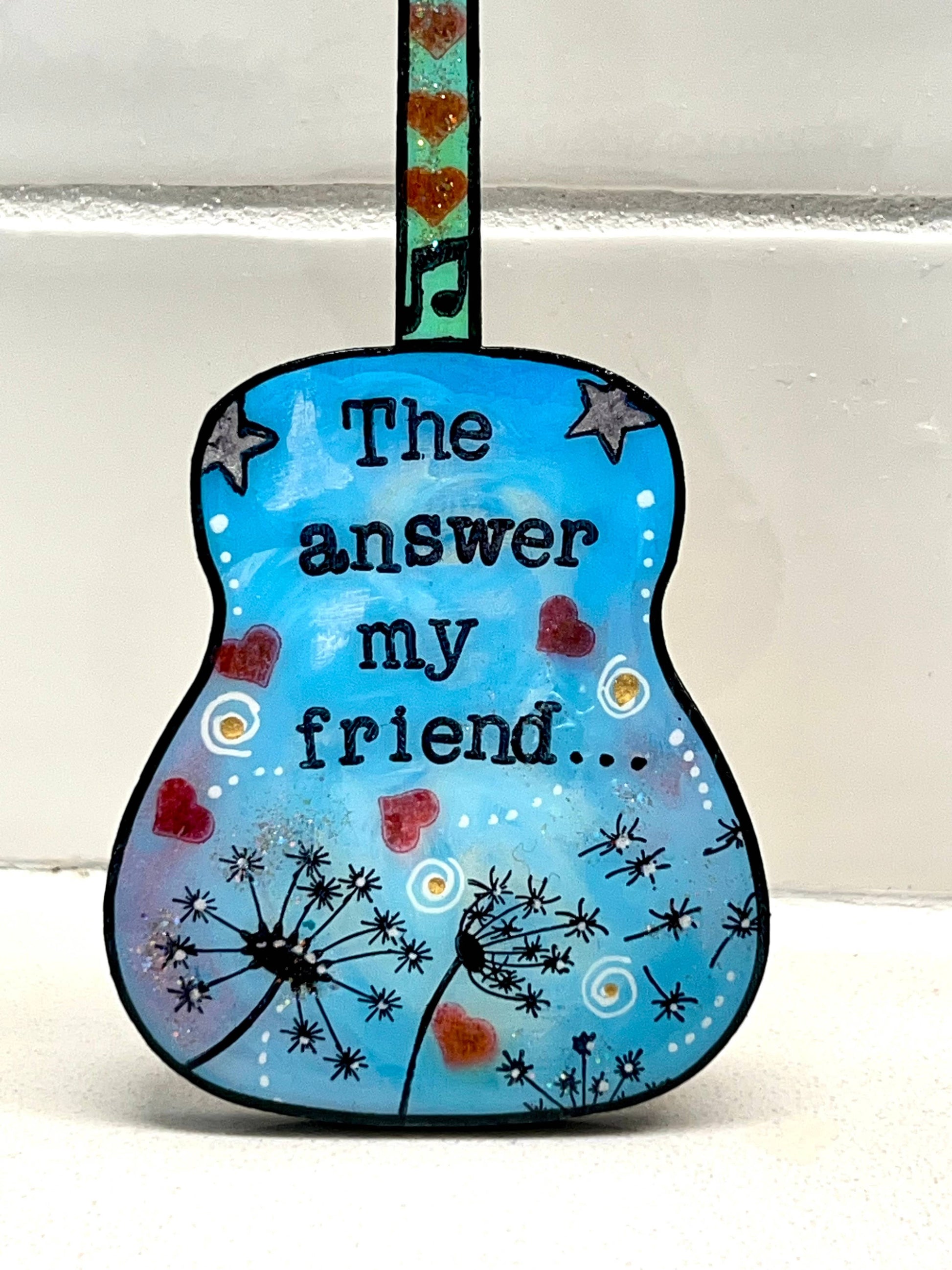 Mellow Monkey hand-painted blue guitar ornament featuring Blowing In The Wind lyrics and dandelion illustrations.