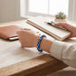 Mellow Monkey light blue and navy matte bead bracelet with silver accent on a person writing in a notebook.