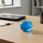 Mellow Monkey blue raspberry SlowFlow squishy apple fidget toy on a wooden desk with office supplies.