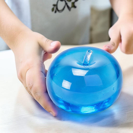 Mellow Monkey blue raspberry SlowFlow squishy apple fidget toy being squeezed by hands on a white desk