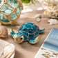 Mellow Monkey 6-inch blue cartoon turtle figurine with a glossy finish, displayed on a wooden table with seashells.