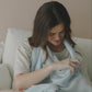 Mellow Monkey Bluebell nursing cover in light blue organic cotton muslin with built-in teether used by a mother