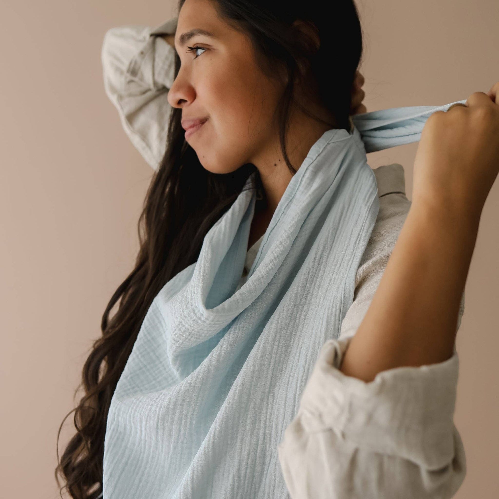 Mellow Monkey Bluebell nursing cover in light blue organic cotton muslin worn by a woman with a built-in teether