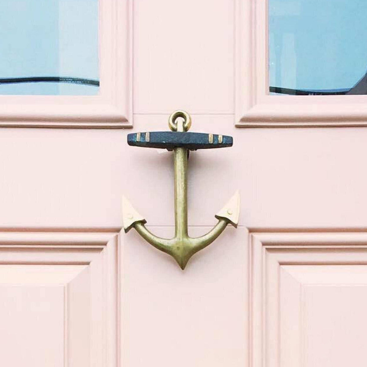 Mellow Monkey solid brass anchor door knocker mounted on a light pink coastal style door