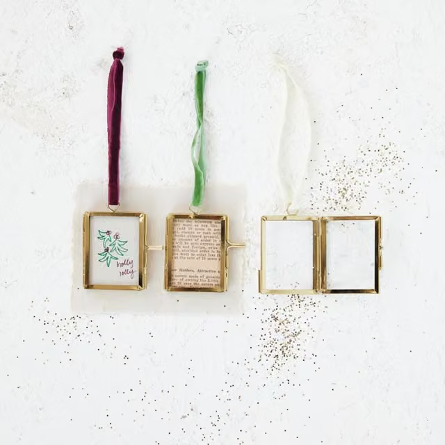 Mellow Monkey brass and glass photo frame ornaments with red, green, and white velvet ribbon hangers on white surface