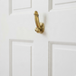Mellow Monkey 8-inch antique gold brass wall hook with a unique phallic design mounted on a white door.