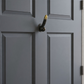 Mellow Monkey 8-inch antique brass wall hook with a unique phallic design mounted on a dark grey door.