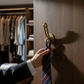 Mellow Monkey antique gold brass wall hook shaped like a phallus holding a striped necktie on a dark wood door