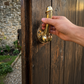 Mellow Monkey 6-inch antique gold brass wall hook shaped like a phallus mounted on a rustic wooden door