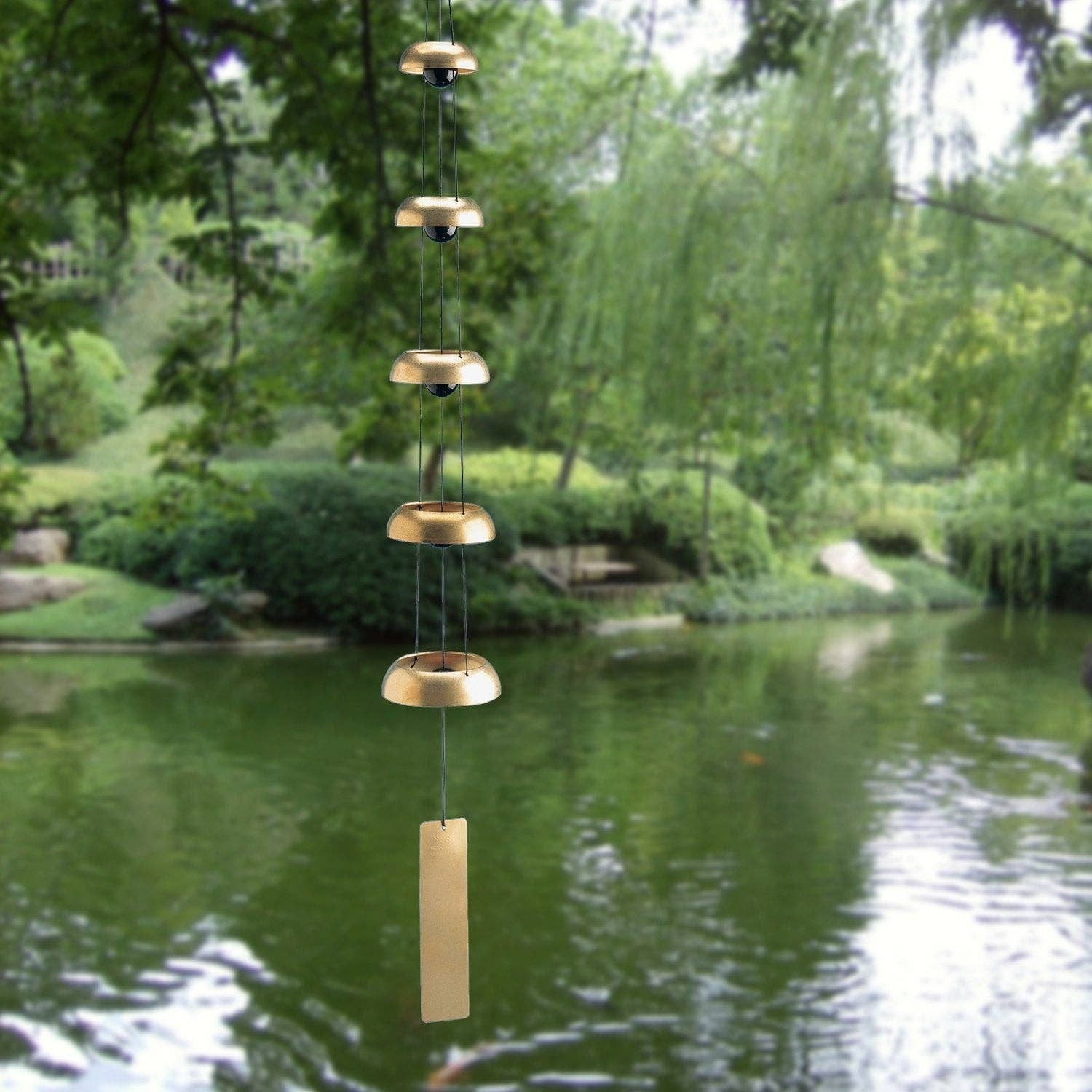 Mellow Monkey Woodstock Temple Bells Quintet featuring five brass bells hanging vertically in a lush garden setting.