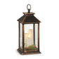 Mellow Monkey bronze lantern with three flameless candles, festive greenery, and red berries, 11.5 inches tall.