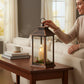 Mellow Monkey bronze lantern with flameless candles and festive greenery on a wooden table in a cozy living room