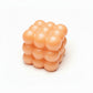 Mellow Monkey 2-inch peach-colored bubble cube stress relief squeeze ball with a smooth, tactile finish.