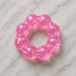 Mellow Monkey Bubblegum Glow Feelzies sensory bracelet in translucent pink with glitter on a marble surface.