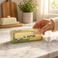 Mellow Monkey Wax Crack Butter Stick squishy toy in realistic packaging held by a hand on a marble kitchen counter