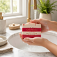 Mellow Monkey Candy Cane Christmas vegan bar soap with red and white stripes being rinsed under a bathroom faucet.