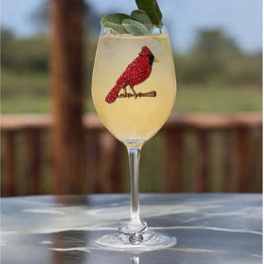 Mellow Monkey stemmed wine glass featuring a red jeweled cardinal bird design, filled with a cocktail and sage garnish