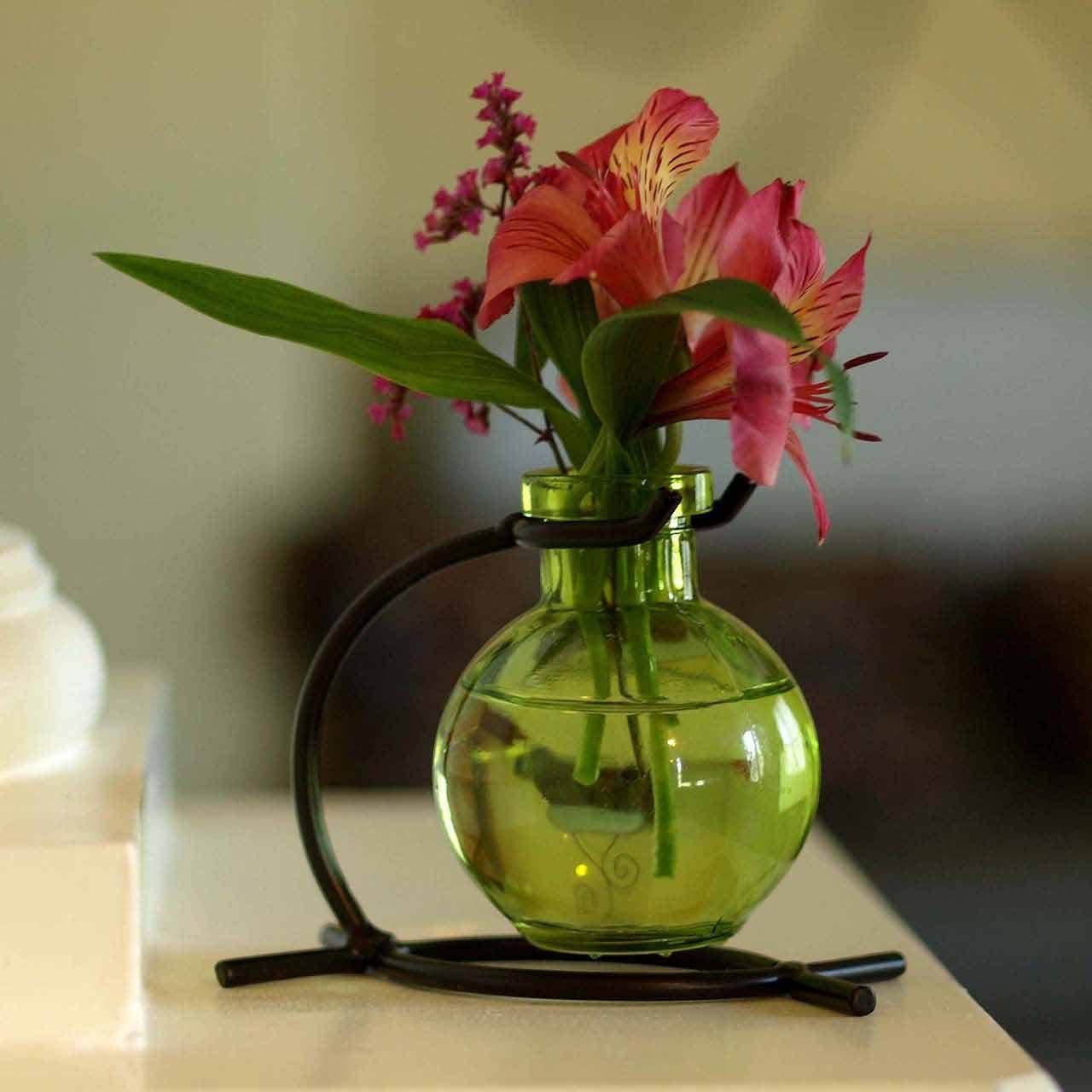 Mellow Monkey Casablanca lime green recycled glass mini vase suspended in a black metal stand with pink flowers.