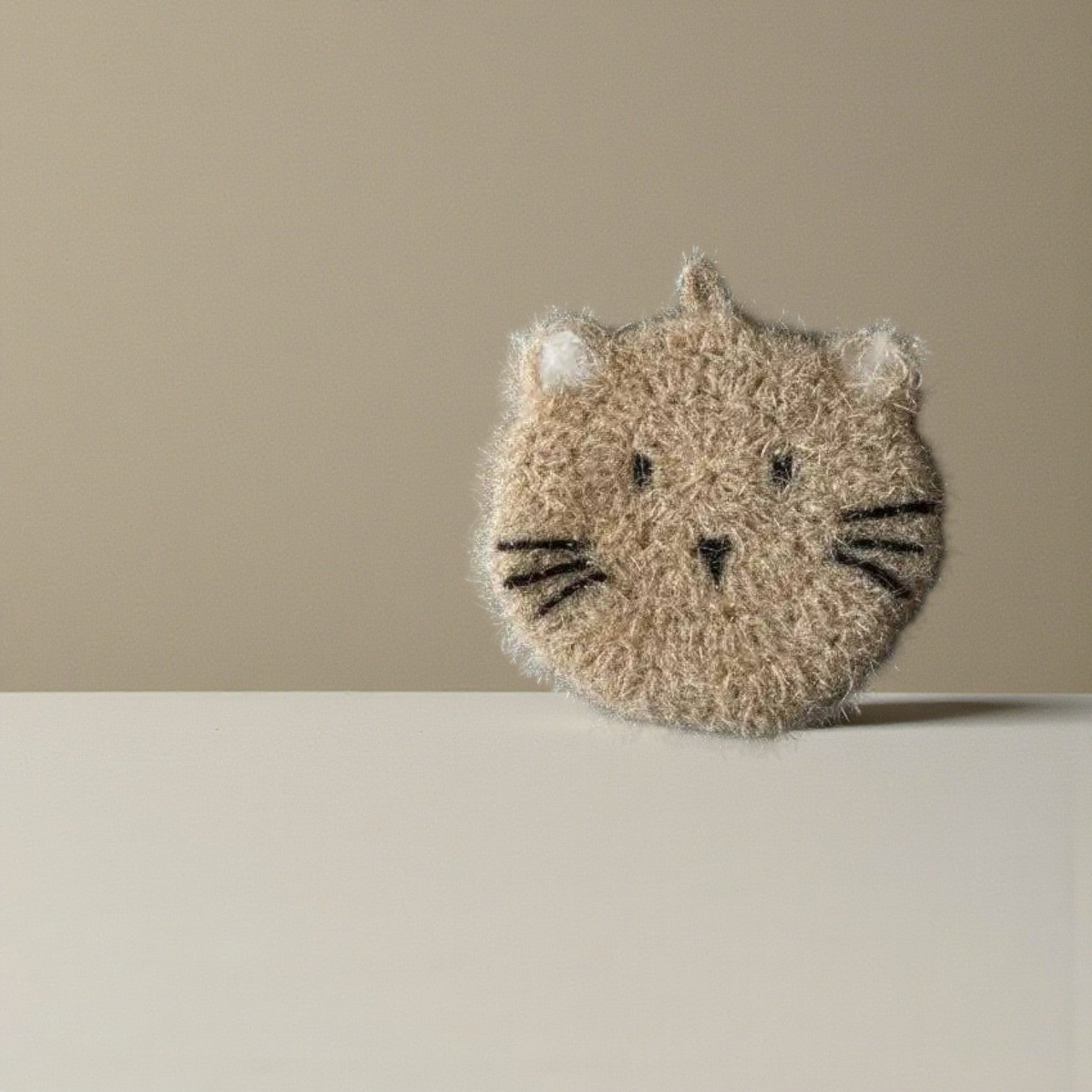Mellow Monkey Moki cat dish scrubber, taupe with black embroidered features and white ear accents. Scrubby texture.
