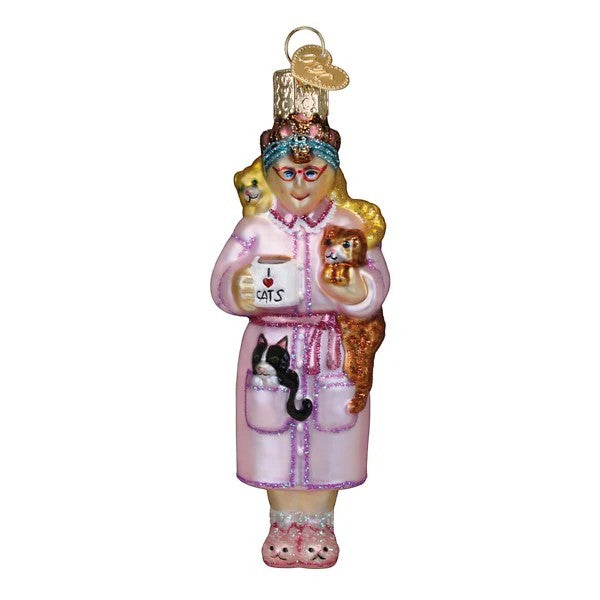 Mellow Monkey Cat Lady ornament, a blown glass figure wearing a pink robe and slippers, holding a mug that says "I love cats" and surrounded by three cats.